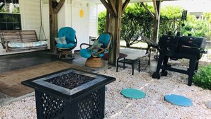 A covered outdoor seating area with a fire pit, two blue chairs, a table, and a grill. - Pet-Friendly 2BR /2 min Walk to Beach /Pool+Hot Tub/ Golf Cart option (North Myrtle Beach)