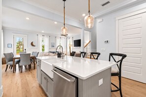 Una cocina moderna con una isla central, electrodomésticos de acero inoxidable e iluminación colgante.