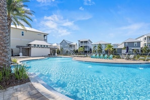 A swimming pool surrounded by multi-story buildings with balconies, a clear blue sky, and some palm trees. - Crabbing Hole Lane - 5BR/4.5BA Prominence Home on 30A - Sleeps 12 - Golf Cart (Rosemary Bch)