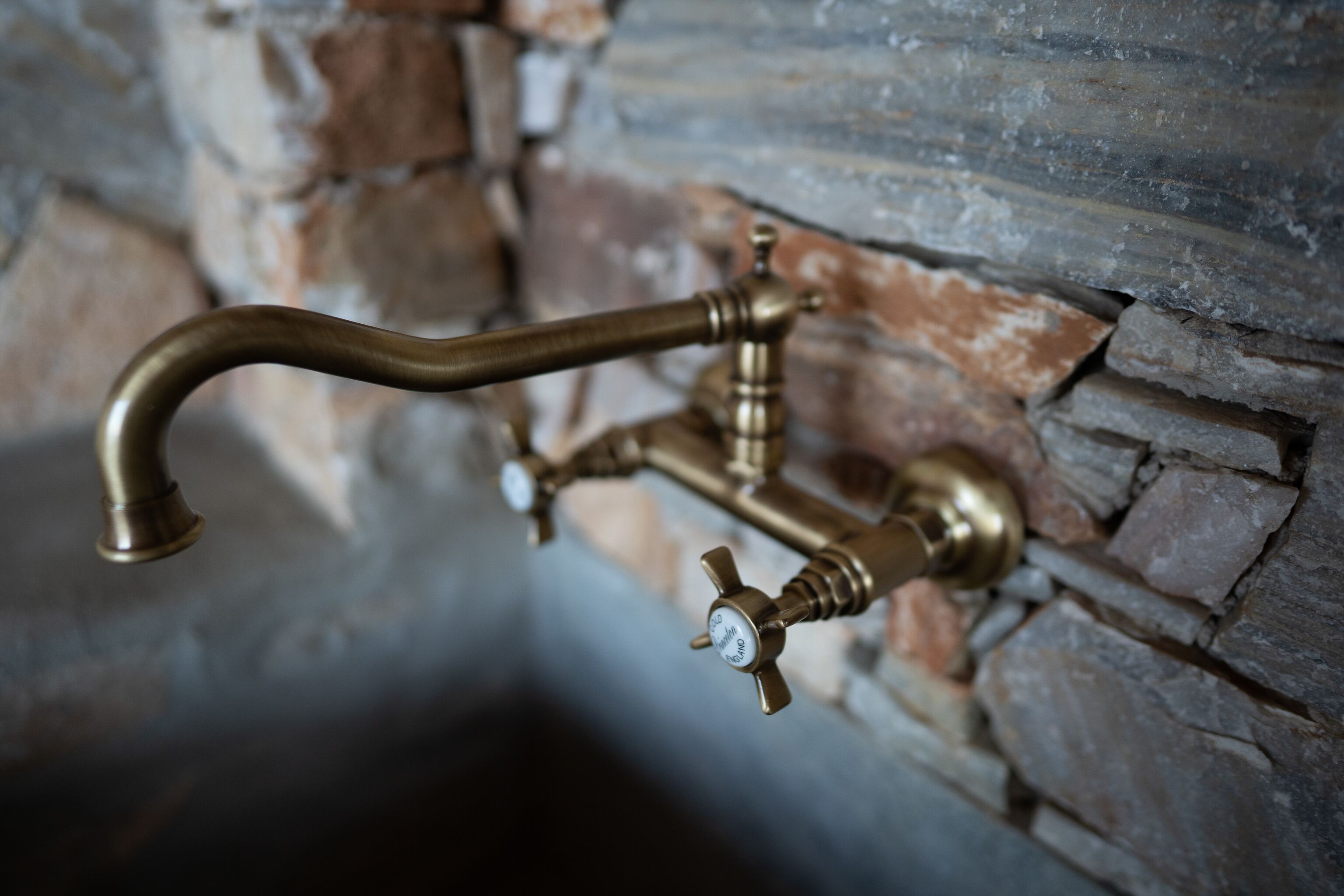 A brass faucet mounted on a stone wall.