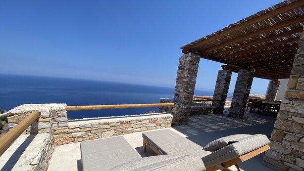 A stone and wood outdoor seating area with a view of the sea. - Blue Calm Luxury Cycladic Villa in Sifnos island  (Αρτεμώνας Sifnos)