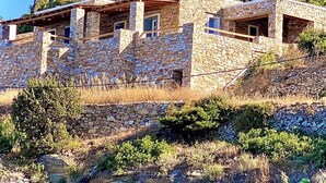 A stone building with multiple rooms, a wooden deck, and a hillside backdrop. - Blue Calm Luxury Cycladic Villa in Sifnos island  (Αρτεμώνας Sifnos)