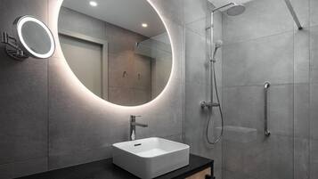 A modern bathroom with a large mirror, a rectangular sink, and a shower area.