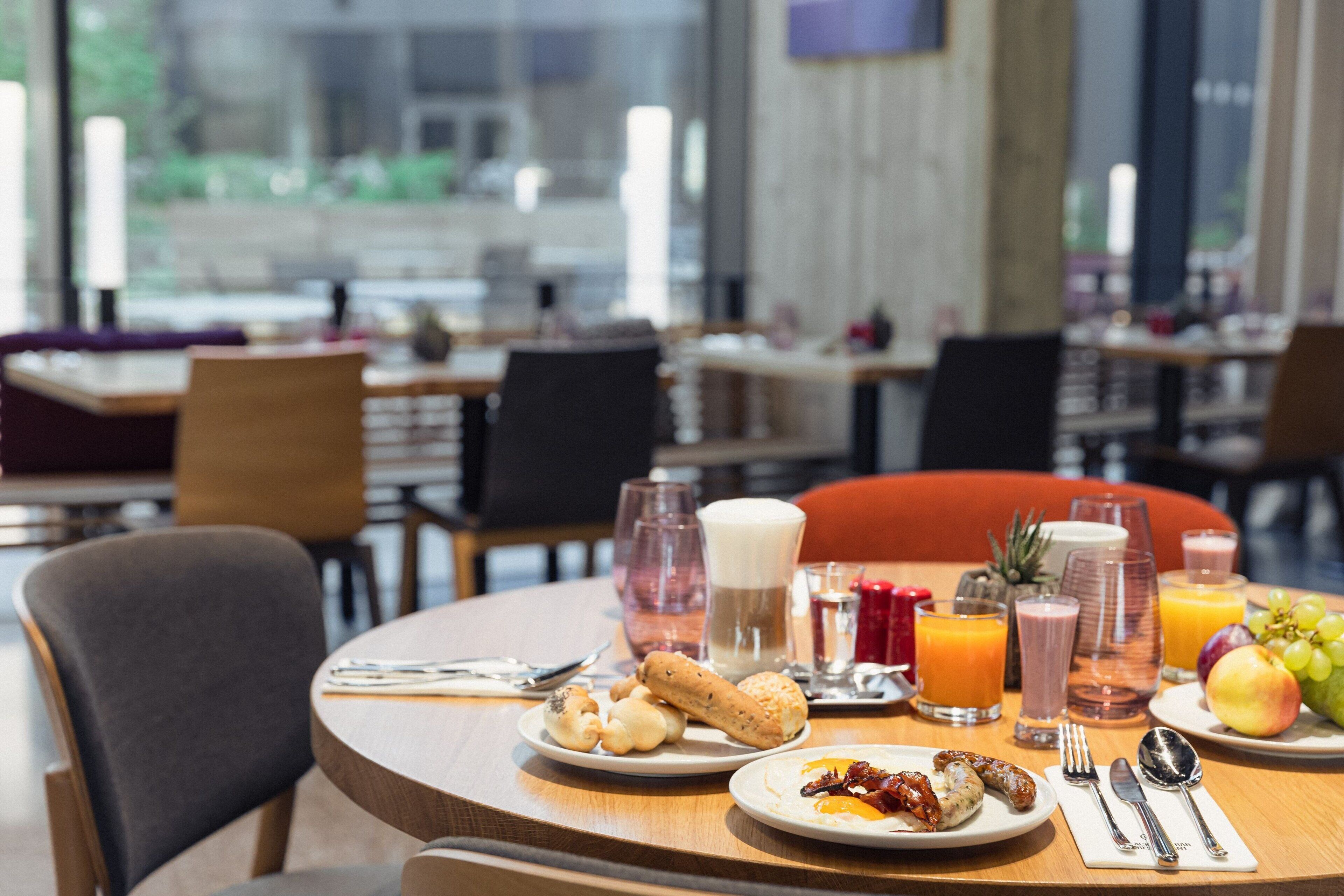 Un desayuno servido con platos de comida, bebidas y utensilios sobre una mesa.