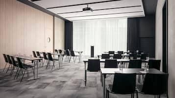 Un salón de conferencias con una larga mesa, sillas, un proyector y un amplio ventanal con cortinas.