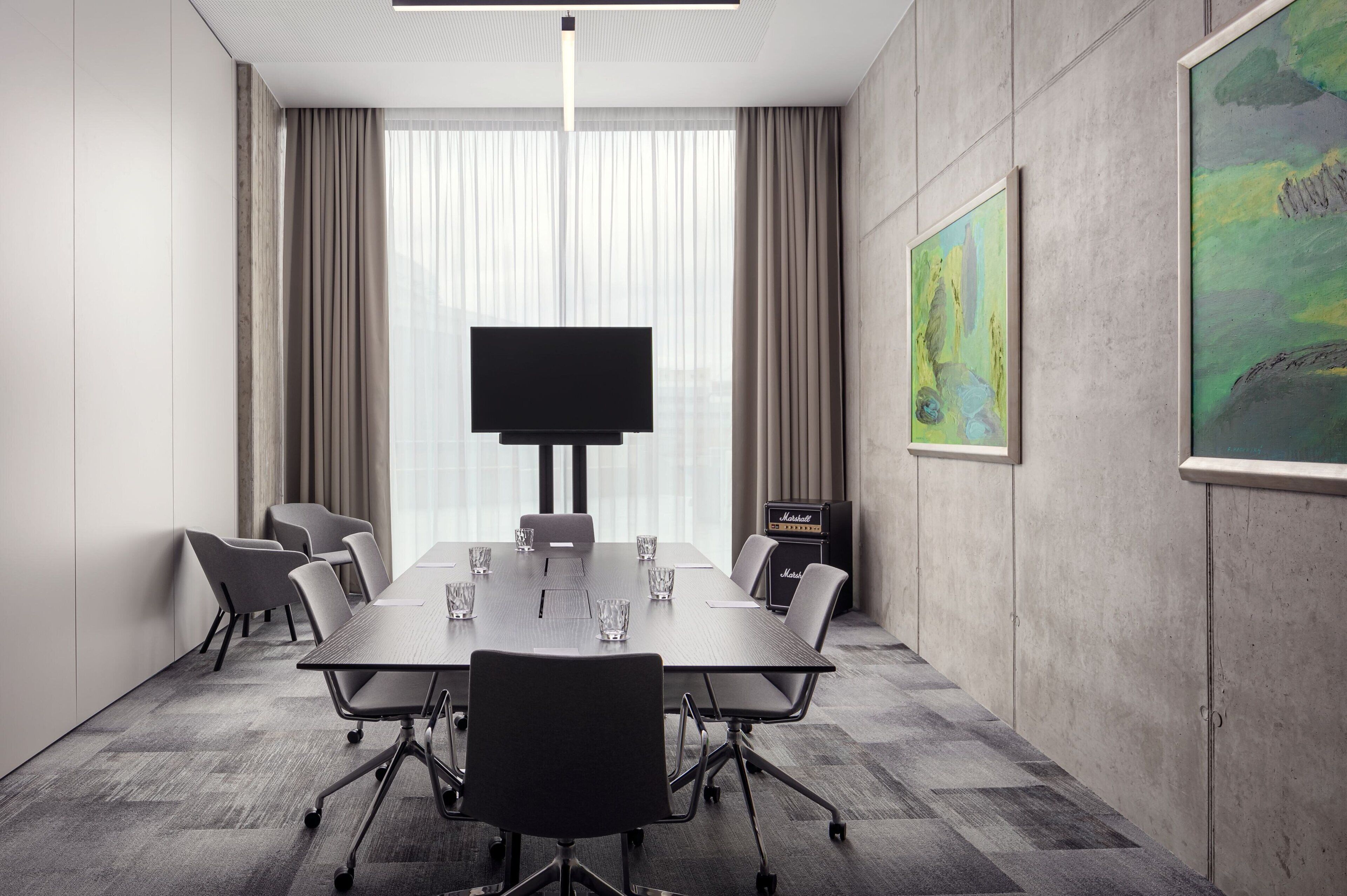 Una sala conferenze con un grande tavolo, sedie, un televisore a schermo piatto e opere d'arte alle pareti.