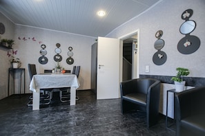 A modern dining area with a table and chairs, decorative wall mirrors, and a door leading to another room.