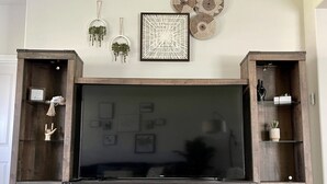 A wooden entertainment center with a flat-screen TV, shelves, and drawers.