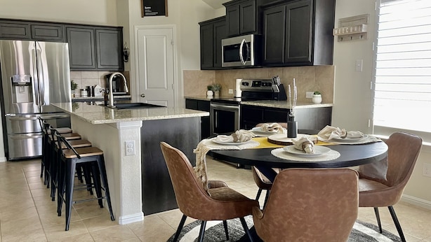 A modern kitchen with dark cabinets, stainless steel appliances, and a central island.