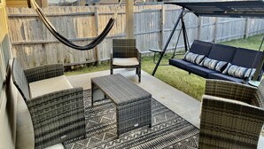 A covered patio area with wicker furniture, a hammock, and a swing.