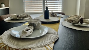 A dining table set with plates, napkins, and a vase.