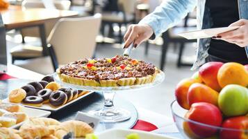 A dining table with a variety of pastries and a fruit bowl.