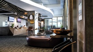 A modern lobby with a reception desk, seating area, and a large window. - Hotel HW Libertad (Santiago)