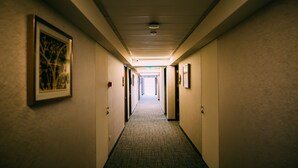 A long, narrow hotel corridor with framed artwork on the walls, doors on both sides, and a carpeted floor. - Hotel HW Libertad (Santiago)