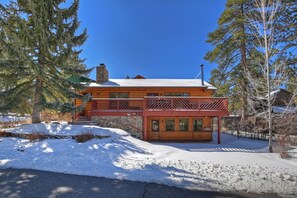 Une cabane en rondins avec un toit enneigé, une façade en bois et un petit porche.