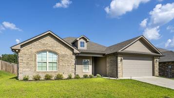 A two-story house with a garage, a large arched window, and a well-maintained lawn.