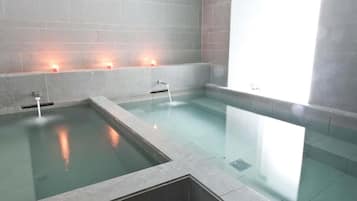 Relax in a serene spa area with a central hot tub and minimalist design.