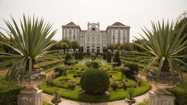 A grand building with a symmetrical facade, a central entrance, and a formal garden with manicured lawns and topiary. - Curia Palace Hotel Spa and Golf (Anadia)