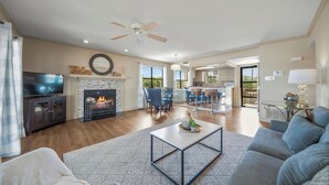 Una sala de estar amplia con chimenea, televisor y ventilador de techo.
