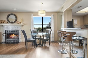 A dining area with a fireplace, a round table, and bar stools.