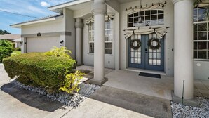 Uma casa de dois andares com varanda coberta, garagem e porta principal adornada com guirlandas.