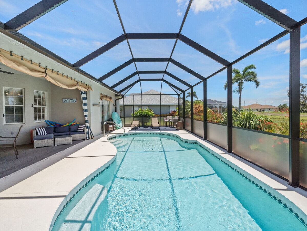 Una piscina cubierta con vistas a una casa y palmeras.