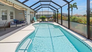 Piscina coberta com vista para uma casa e palmeiras.