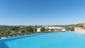 A clear blue swimming pool with lounge chairs and a view of a residential area in the background. - Vale Da Ribeira Residences (Portimao)