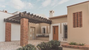 A courtyard with a pergola, brick pillars, tiled flooring, and a small garden area. - Vale Da Ribeira Residences (Portimao)
