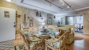 Un coin repas avec une table en verre entourée de chaises en osier, d’un canapé et d’une table à manger avec des chaises.