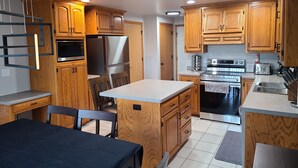 A modern kitchen with wooden cabinets, stainless steel appliances, and a central island with seating.