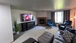 A living room with a television, fireplace, sofas, and a potted plant.