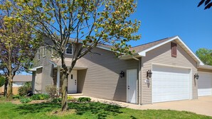 A two-story house with a garage, a front porch, and a tree in the yard.