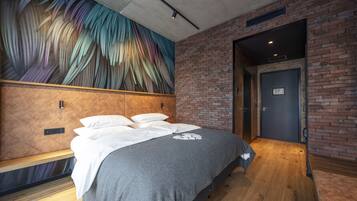 A modern hotel room with a large bed, a brick wall, and a mural on the ceiling.