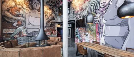 A modern lounge area with a large mural, leather seating, and pendant lighting.
