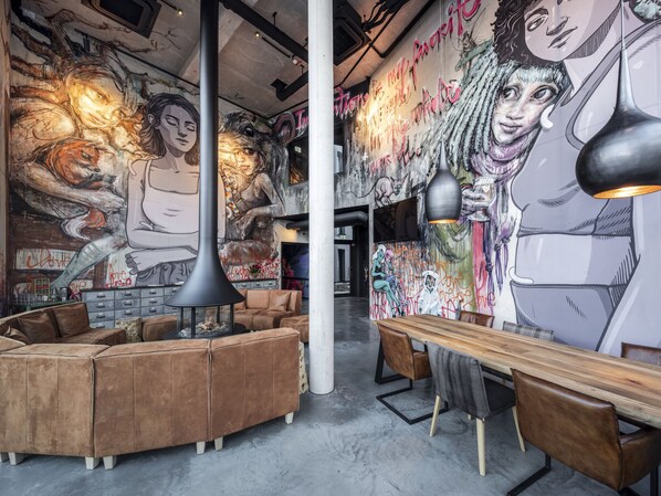 Un área de estar moderna con un gran mural, asientos de cuero e iluminación colgante.