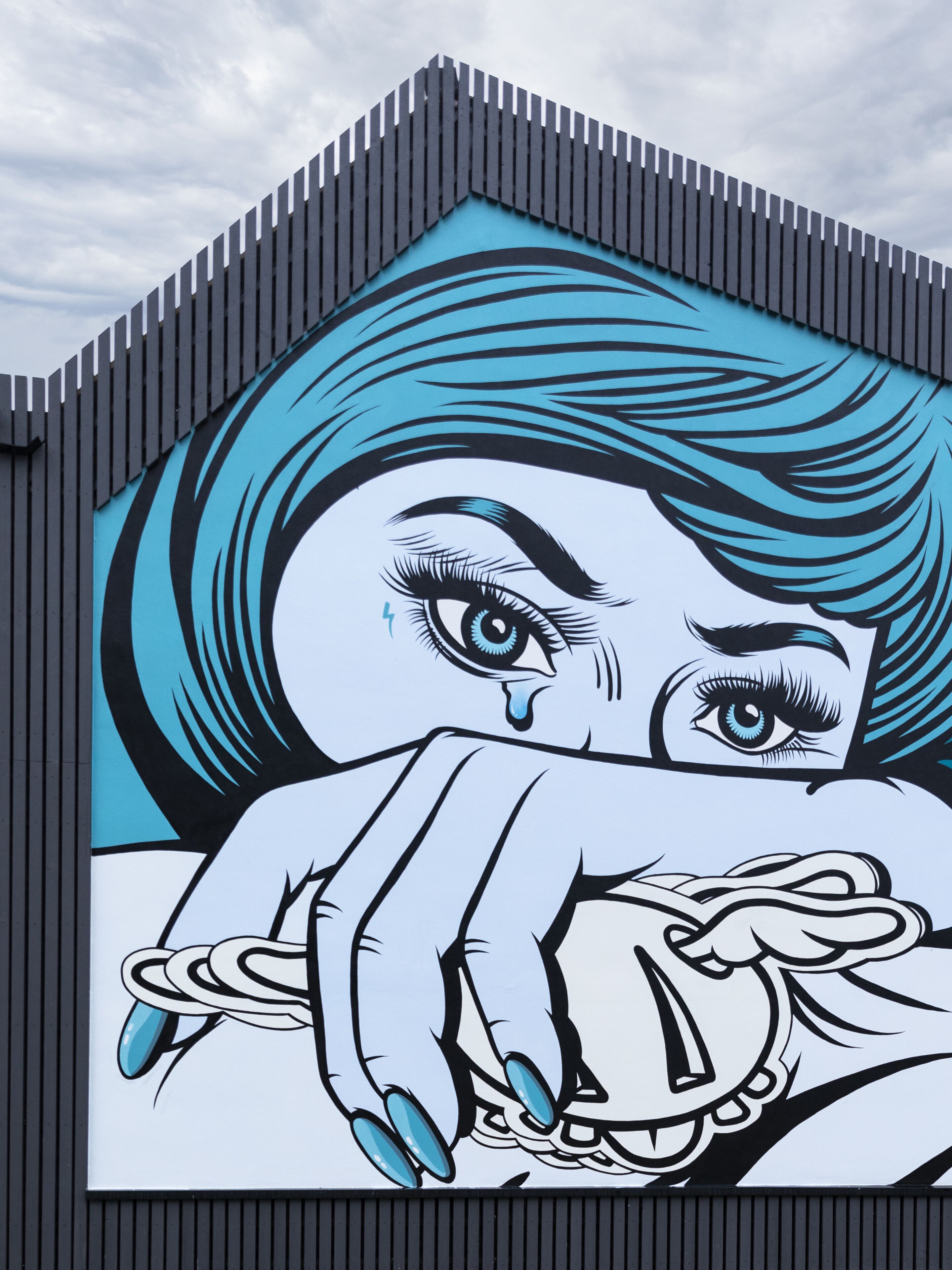 Un bâtiment orné d’une fresque murale remarquable, aux couleurs bleu et blanc, représentant un visage.