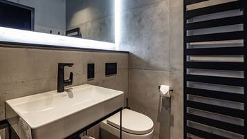 A modern bathroom with a white sink, black faucet, and a toilet.
