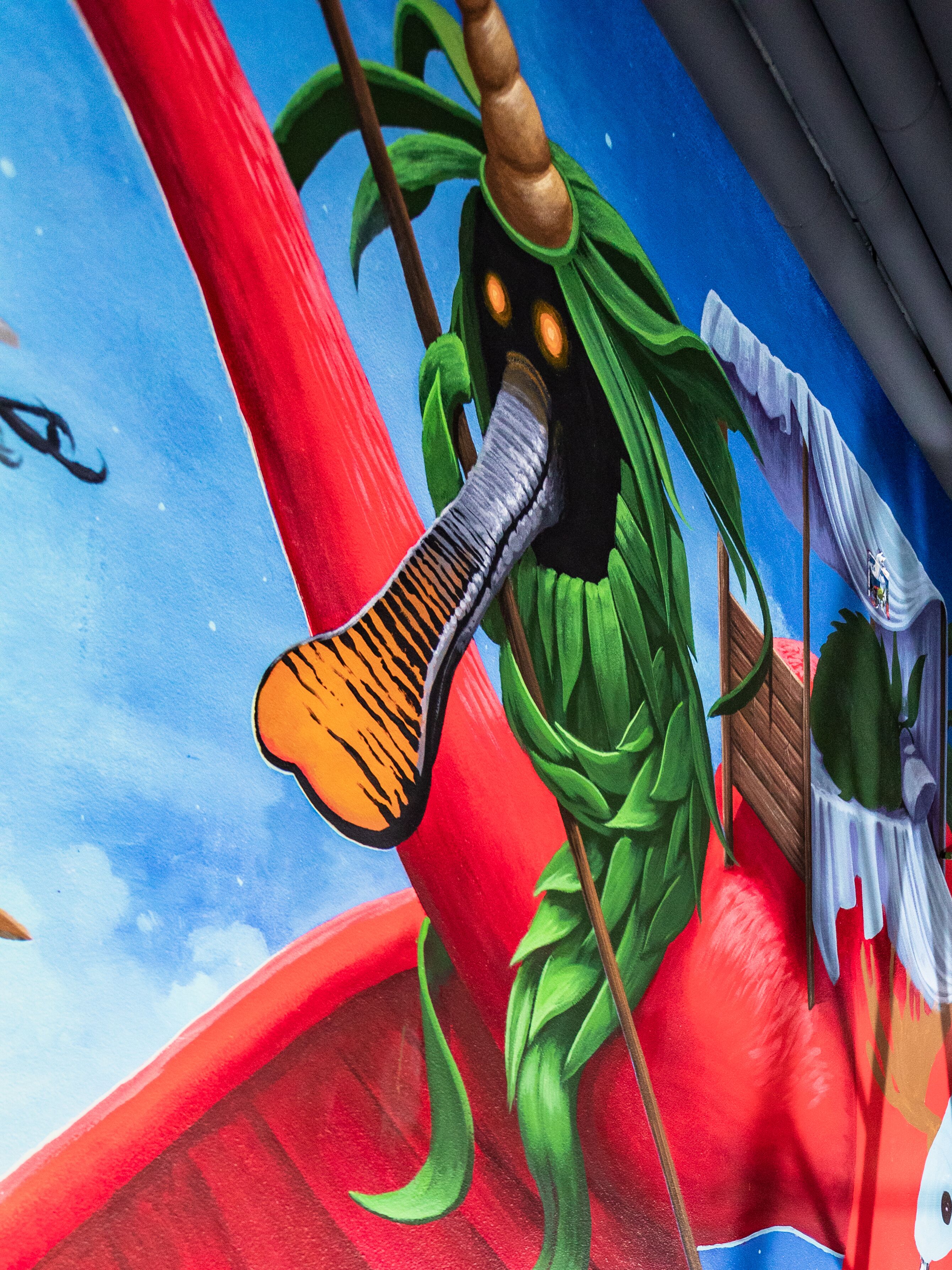 A mural with a character holding a large red staff, a green cloak, and a white hat.