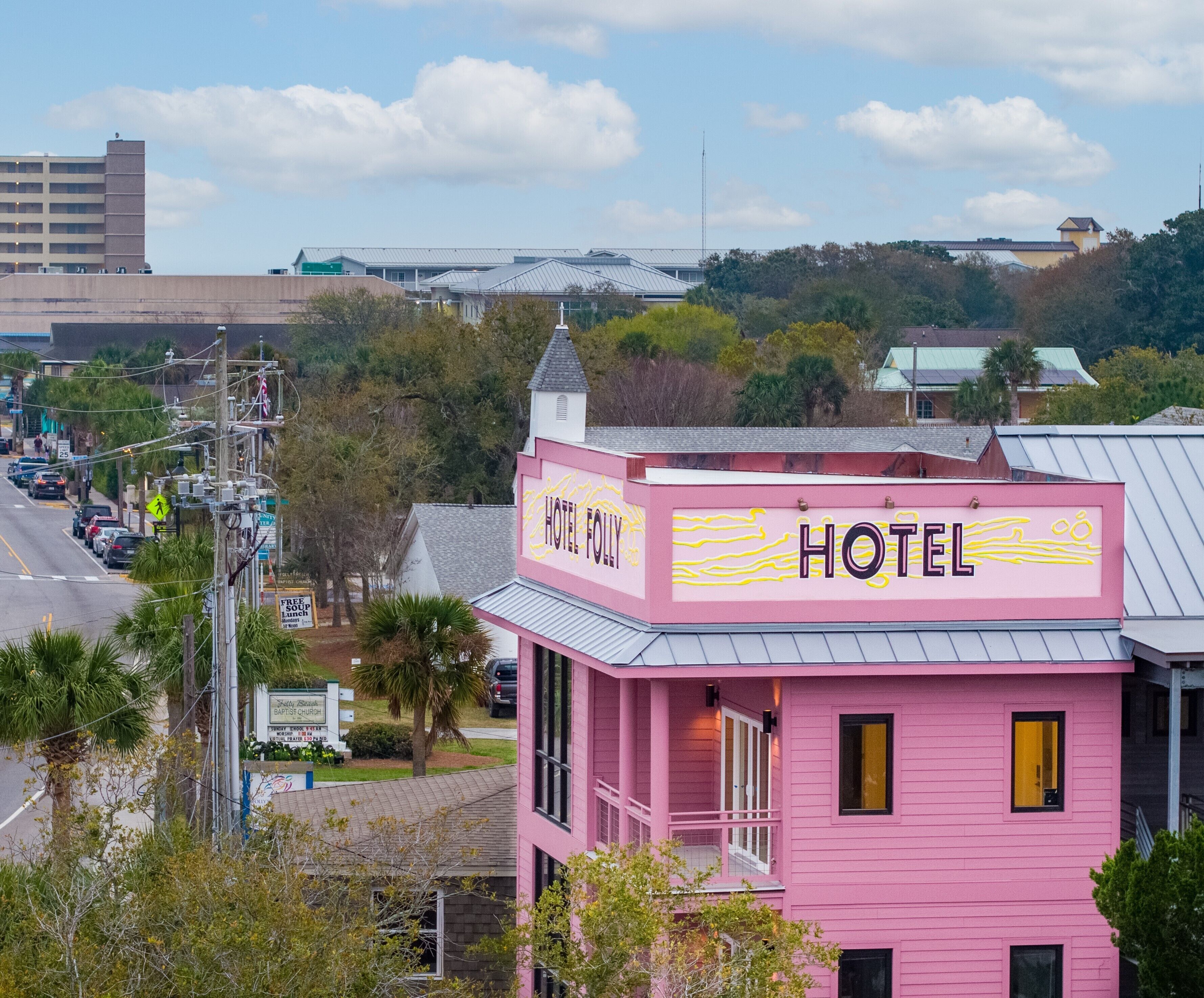 A pink building with a sign that reads 'HOTEL FOLLY.'