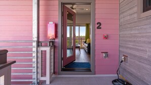 Ein pinkfarbenes Gebäude mit einer Tür, die auf einen Balkon führt.