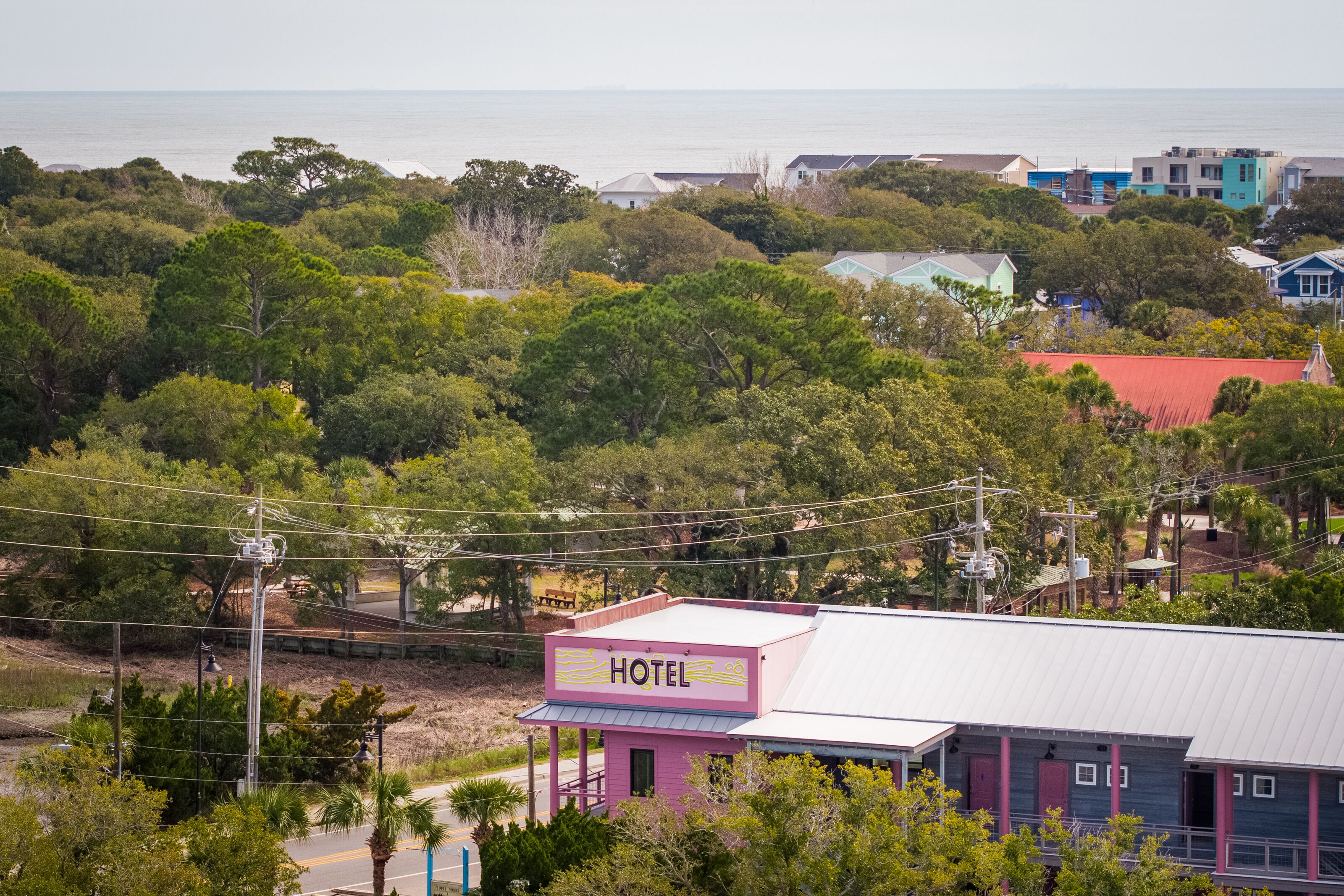 Un edificio rosa con un cartel que dice 'HOTEL' y vista al océano de fondo.