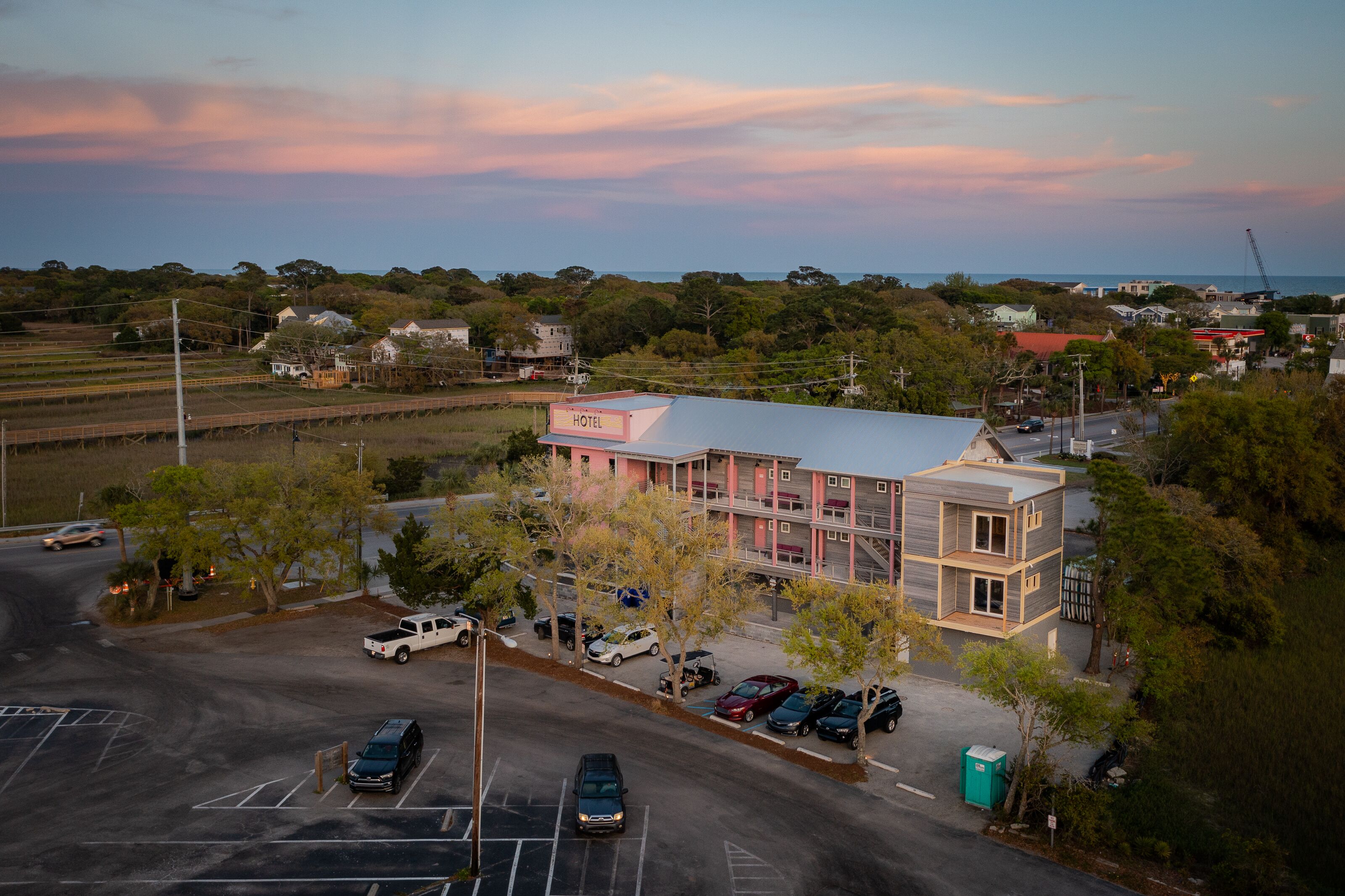 A hotel with a modern design, located near a parking area with several cars.