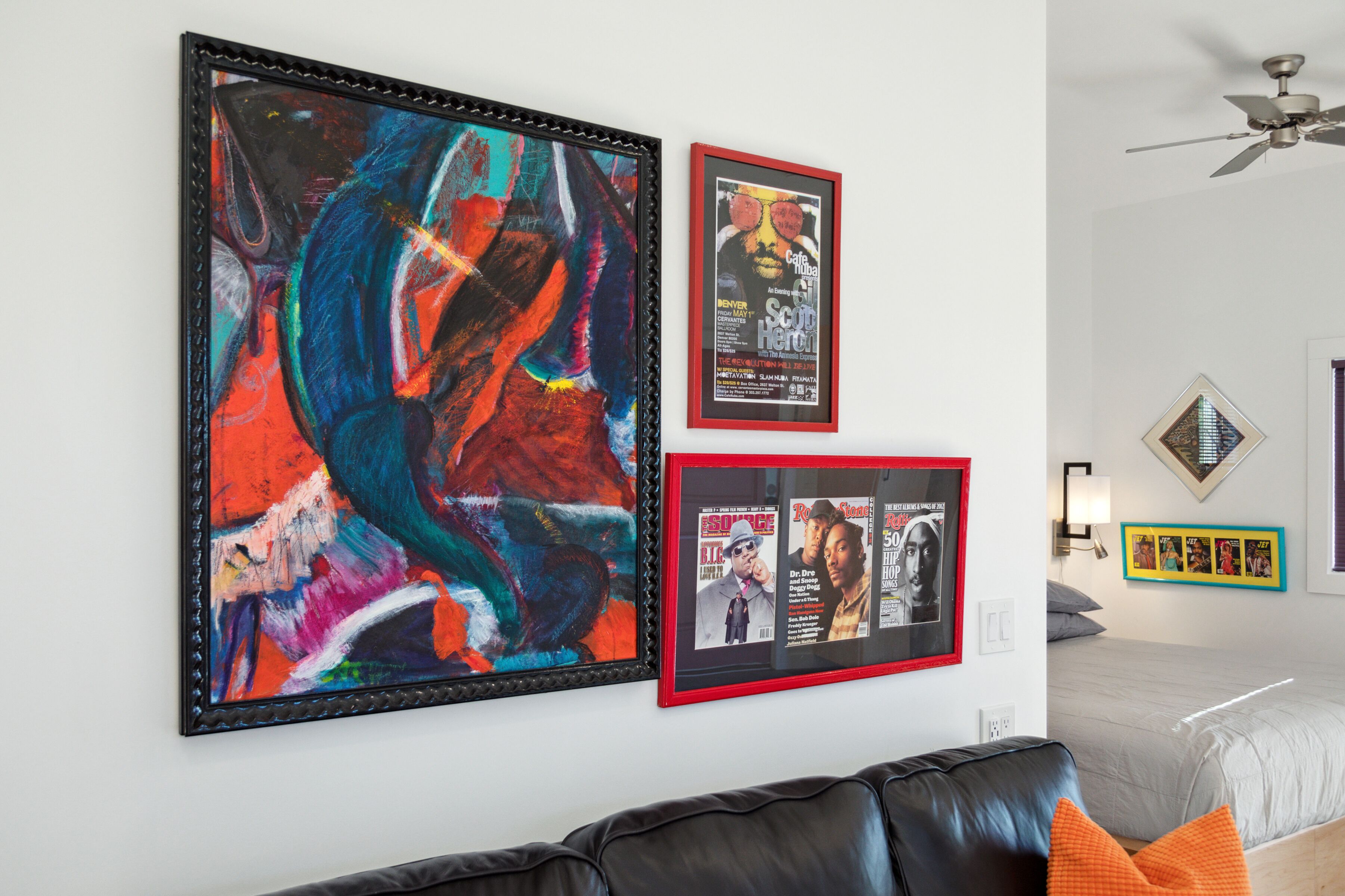 A room with a large abstract painting, a framed movie poster, and a smaller framed picture on the wall.