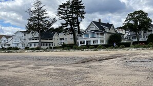 Zona residencial con casas a lo largo de una playa, con costa rocosa y cielo nublado.