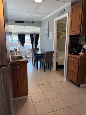A kitchen with a dining area, wooden cabinets, a coffee maker, and a view of the outdoors.