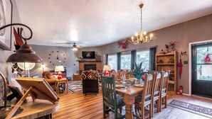 A cozy living room with a fireplace, wooden furniture, and a chandelier. - Gotch Eyed Moose by Ruidoso Vacation Rentals (Alto)