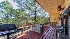 A covered deck with a grill, seating, and a deer head decoration. - Gotch Eyed Moose by Ruidoso Vacation Rentals (Alto)
