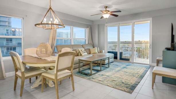 A spacious living room with a dining table, chairs, a sofa, and a ceiling fan.