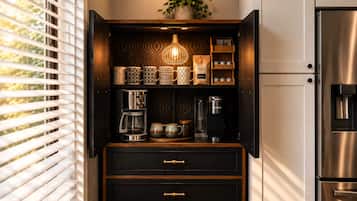 A kitchen with a built-in coffee machine, a coffee maker, and a refrigerator.